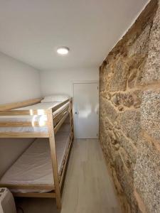a room with bunk beds and a stone wall at Apartamento playa Vigo in Vigo