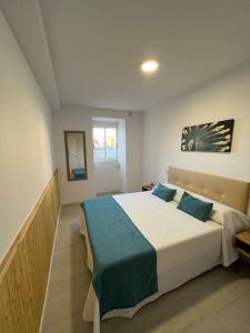 a bedroom with a large white bed with blue pillows at Apartamento playa Vigo in Vigo