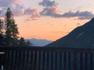 einen Sonnenuntergang in den Bergen mit einem Zaun in der Unterkunft Neuwertiges 2-Zi-Ferienchalet 55m2 in Monstein