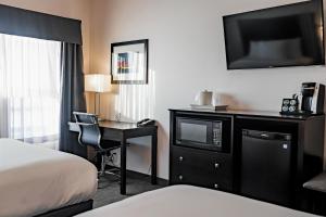 a hotel room with a bed and a desk with a television at Park Inn by Radisson Edmonton Airport in Leduc