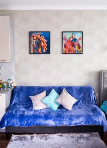 un divano blu in soggiorno con tre foto sul muro di Апартаменты с этническими мотивами с видом на горы a Almaty