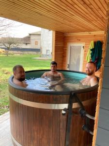 Drei Männer sind in einem Whirlpool in einem Holz in der Unterkunft Le Riolet in Marsac-en-Livradois