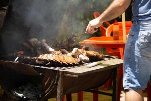 Un homme cuisine de la nourriture sur un grill dans l'établissement Casa Charlie, à Areguá