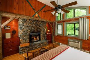 a dining room with a stone fireplace in a log cabin at Friends Lake Inn in Chestertown