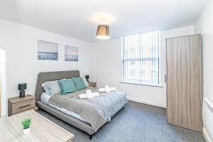 1 dormitorio con cama, mesa y ventana en Winckley House Serviced Apartments in Preston, en Preston