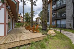 ein Holzdeck mit Bänken neben einem Gebäude in der Unterkunft Rosa Edifício Bav in Gramado
