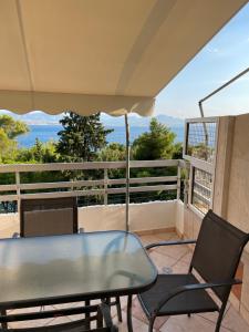 a table and chairs on a balcony with a view of the ocean at Neraida Central Apartment in Loutraki