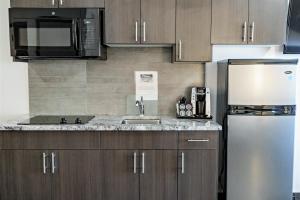 a kitchen with a sink and a refrigerator at Park Inn by Radisson Edmonton Airport in Leduc