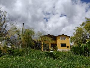 a yellow house sitting on top of a lush green field at Iwoka Ecoturismo in La Calera