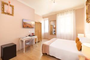 a hotel room with a bed and a desk in it at Colibrì Prestige Rooms - Roman Ruins View in Cagliari