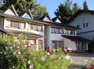 una casa con flores delante en LA PONDEROSA Apart Hotel en San Carlos de Bariloche