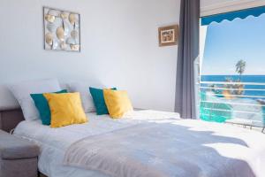 sypialnia z łóżkiem z żółtymi i niebieskimi poduszkami w obiekcie Apartment With Panoramic Sea View, Walk To The Beach - Maréchal Juin by Halldis w Cannes