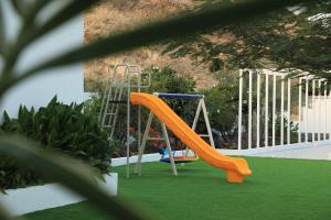 un tobogán naranja en un parque infantil con césped verde en Quiet House villa en Hatta