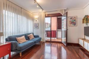 a living room with a blue couch and a sliding glass door at Precioso apartamento en Sopela in Sopelana