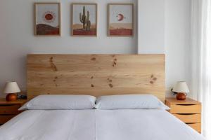 a bedroom with a white bed with three pictures on the wall at Precioso apartamento en Sopela in Sopelana