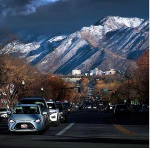 a busy street with cars parked in front of a snow covered mountain at Metropolitan Inn Downtown Salt Lake City in Salt Lake City