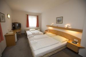 Zimmer mit 2 Betten, einem Schreibtisch und einem TV in der Unterkunft Gasthof Weingrill in Friesach