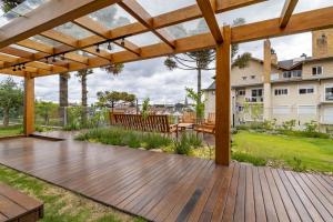 una terraza de madera con pérgola en el patio trasero en Rosa Edifício Bellagio Canela com Infraestrutura completa, en Canela