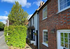 une maison en briques avec un arbre à côté d'une rue dans l'établissement Pieman's Cottage - Pulborough, West Sussex Cottage - sunny courtyard, à Pulborough