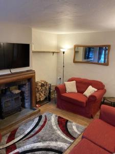 a living room with a red couch and a flat screen tv at Pieman's Cottage - Pulborough, West Sussex Cottage - sunny courtyard in Pulborough