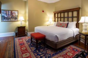 um quarto com uma cama com um banco vermelho e 2 candeeiros em The Marshall House, Historic Inns of Savannah Collection em Savannah