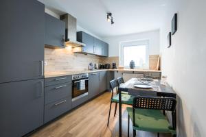 cocina con armarios azules, mesa y sillas en Arbio I Cozy Apartments Augsburg-Lechhausen, en Augsburg