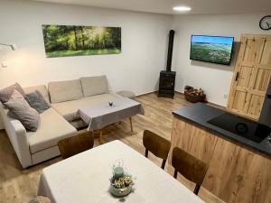 a living room with a couch and tables and a television at Chalupa pod lipenskou hrází in Loučovice