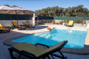 a swimming pool with chairs and an umbrella at Casa da Ti´Lola in Évora