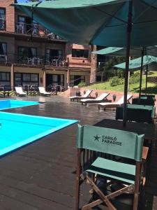 a chair sitting next to a swimming pool with an umbrella at Cariló Paradise Apart Hotel & Spa in Carilo