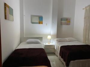 1 dormitorio con 2 camas y mesita de noche con lámpara en Casa Olguita, en Manta