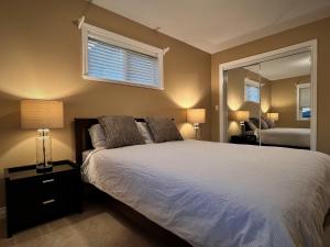 a bedroom with a white bed and a mirror at Lovely J Home -Stunning river view cozy two bedroom private suite in New Westminster