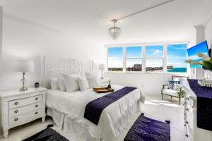 a white bedroom with a bed and a window at Modern beachfront condo with pool, gym and tennis in Marco Island +29 photos