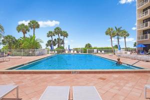 a swimming pool in a resort with palm trees at Modern beachfront condo with pool, gym and tennis in Marco Island