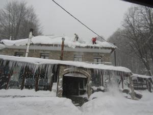 dos personas en el techo de una casa cubierta de nieve en To Hani Tou Kokkini, Pelion en Chania