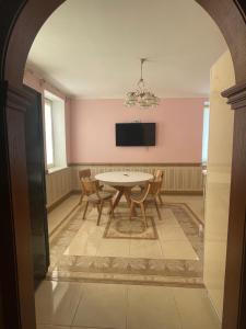 uma sala de jantar com mesa e cadeiras e uma televisão em Lux House em Chernivtsi