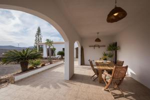 un patio con mesa, sillas y un arco en Casa El Kornao, Fuerteventura, en Tuineje