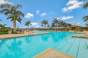 una piscina en un resort con palmeras en Modern waterfront home in Artesia with pool/gym, en Lely Resort