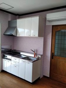cocina con armarios blancos, fregadero y puerta en Cafe panorama - Vacation STAY 96734v, en Esumi