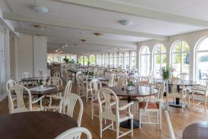 a dining room with tables and chairs and windows at Möckelsnäs Herrgård in Diö