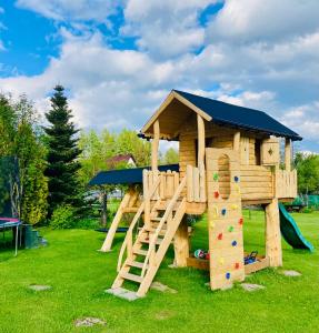 a wooden playground with a slide and a play house at Agroturystyka Pod Modrzewiem in Zubrzyca Górna