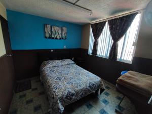 a bedroom with a bed and two windows at Casa Azul Aragon in Mexico City