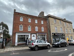 twee auto's geparkeerd voor een bakstenen gebouw bij Glastonbury Town Centre, Lovely 2 Bedroom Apartment in Glastonbury