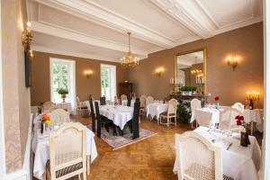 un restaurant avec des tables et des chaises blanches ainsi qu'un miroir dans l'établissement Château de Bellefontaine - Teritoria, à Bayeux