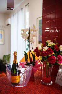 a bottle of champagne and a vase of flowers on a table at AmoCatania Apartment in Catania