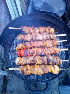 a bunch of skewers of food cooking on a grill at Dollys Den bell tent in St. Just