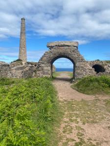 an old stone wall with an arch and a tower at Dollys Den bell tent in St. Just +8 photos