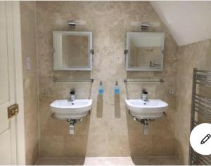 a bathroom with two sinks and two mirrors at Dundee Beds in Dundee