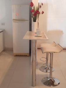 une table et un tabouret avec un vase de fleurs. dans l'établissement Casa kukycita, à San Salvador de Jujuy