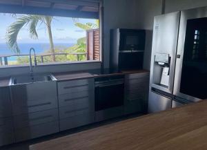a kitchen with a sink and a refrigerator and a window at Location Open Sky in Deshaies
