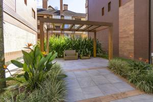 um pátio exterior com uma pérgola e plantas em Rosa Edifício Valle Dell Art em Gramado